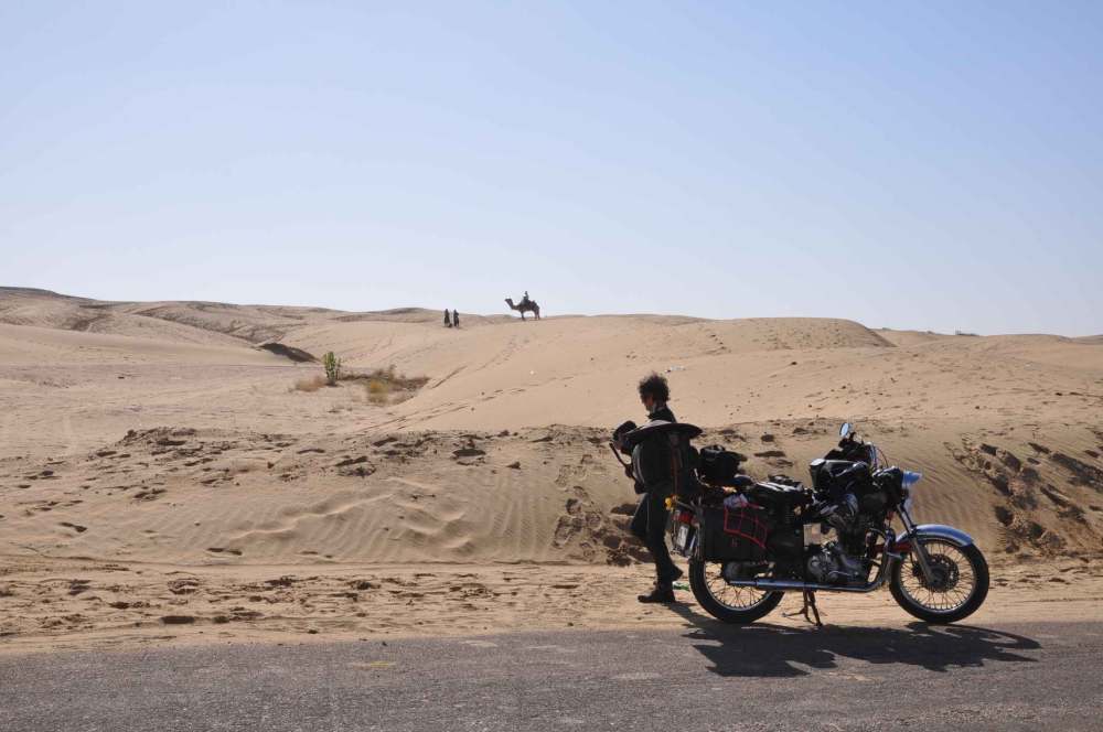 Bike and traveller at the side of road in desert